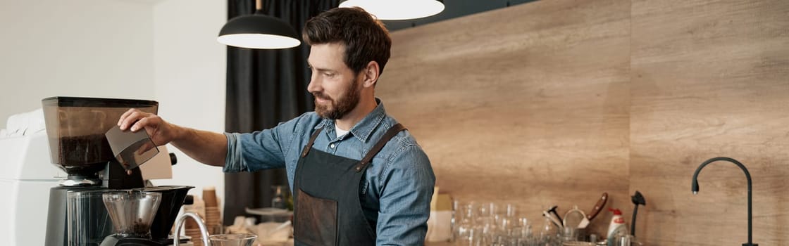 Barista grinds coffee beans before making coffee at coffeehouse