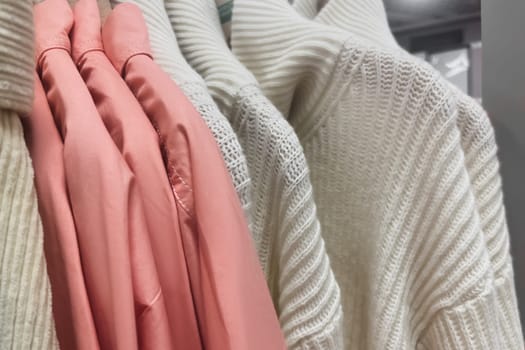 Pullover and sweaters hang on a hanger in the store Row