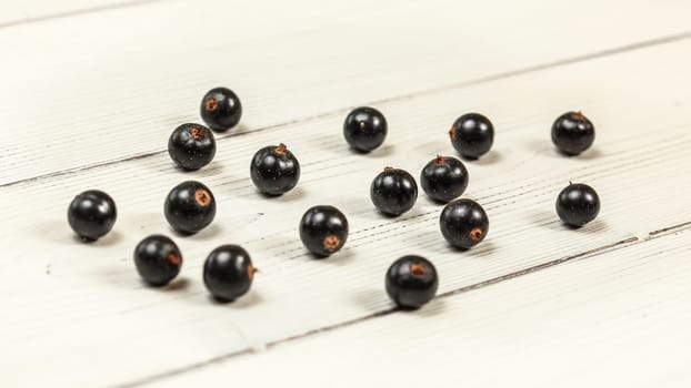 Blackcurrants (Ribes nigrum) spilled on white boards desk