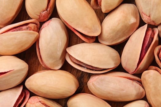 Tabletop view, closeup of turkish red pistachios on wooden board.