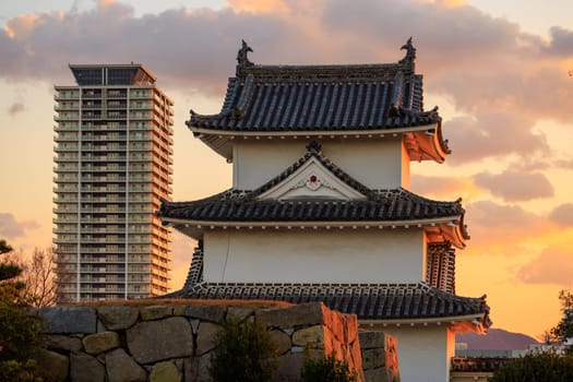 Sunset over watchtower in Japanese castle and modern high rise apartment building. High quality photo