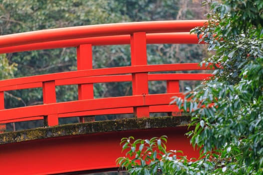 Closeup view of red railing on arched bridge in forest. High quality photo