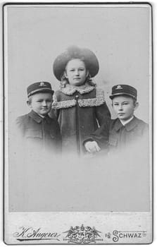 SCHWAZ - TIROL, AUSTRIA-HUNGARY - CIRCA 1900: Vintage cabinet card shows portrait of cute siblings two brothers and hers sister. Edwardian fashion. Photo was taken in a photo studio. Photo was taken in Austro-Hungarian Empire or also Austro-Hungarian Monarchy