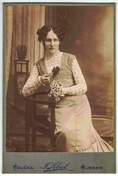 POLICKA, SKUTEC, AUSTRIA-HUNGARY - CIRCA, 1900: Vintage cabinet card shows woman posing in a photo(graphic) studio. Photo was taken in Austro-Hungarian Empire or also Austro-Hungarian Monarchy