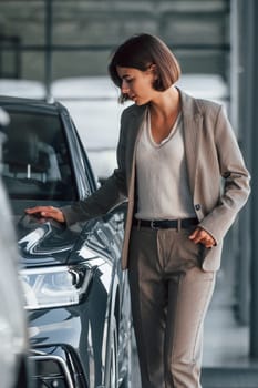 Woman is indoors near brand new automobile indoors.