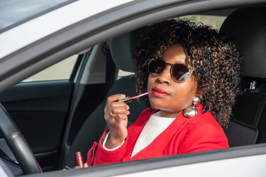 Pretty african american woman in a car doing makeup while standing in a traffic jam, concept a modern married business woman with children saves time, High quality photo