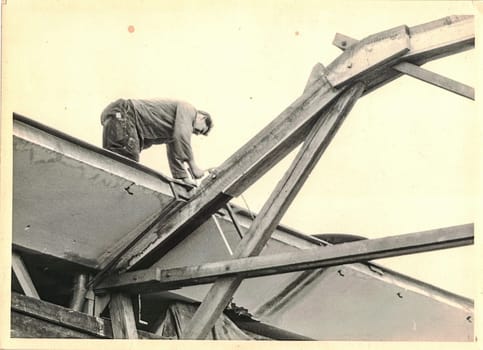 FRAUREUTH, EAST GERMANY - MAY 13, 1965: The retro photo shows carpenter works on roof. Image from Communist bloc. Former East Germany, 1960s.