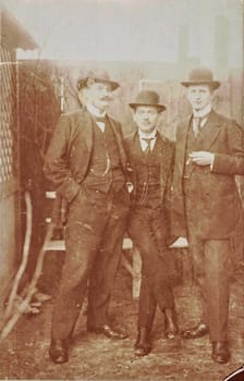 GERMANY - CIRCA 1905: Vintage cabinet card shows dandy men wear bowler hats, luxury garment and one holds cigar. Antique black and white photo. Original photo with imperfection.