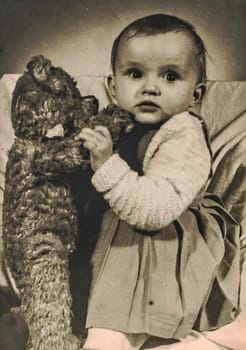 ZWICKAU, EAST GERMANY - CIRCA 1970s: The retro photo shows baby girl with Teddy bear. Studio photo.