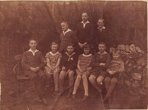 GERMANY - 1929: Vintage photo shows group of young people pose outdoor. Photo with sepia effect.