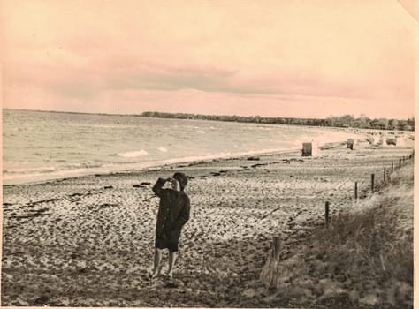 GERMANY - CIRCA 1960s: Retro photo shows woman seeing sealine at the seashore of the Baltic Sea. Retro black and white photo.
