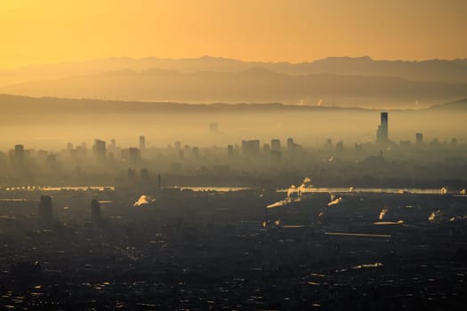 Early morning haze over city and factories with orange glow in sky. High quality photo