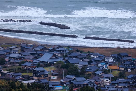 Waves hit concrete breakwater protecting small coastal village. High quality photo