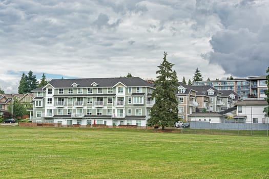New residential low-rise building with huge green lawn in front on cloudy day in Canada