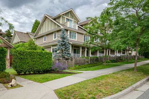 Row of townhouses with concrete pathway in front. Residential townhouses on cloudy day in Vancouver