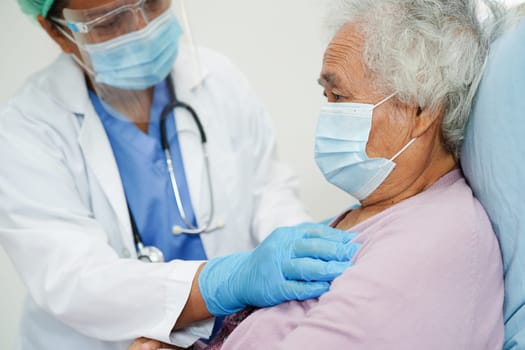 Doctor in ppe user infrared thermometer to check temperature of asian elderly woman patient for safety to protect covid 19 virus.