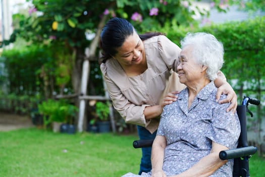 Caregiver help Asian elderly woman disability patient sitting on wheelchair in park, medical concept.