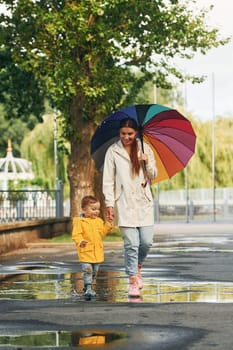 Mother with her son is having a walk outdoors in the park after the rain.