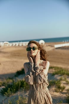 portrait of a smiling woman in a light dress and sunglasses holding her hands near her face. High quality photo