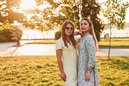 Two women standing in the autumn park together. Beautiful sunshine.