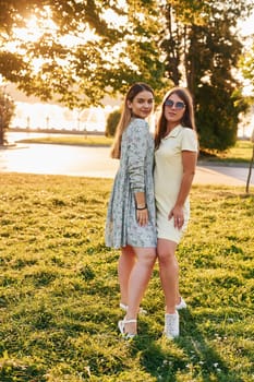 Two women standing in the autumn park together. Beautiful sunshine.