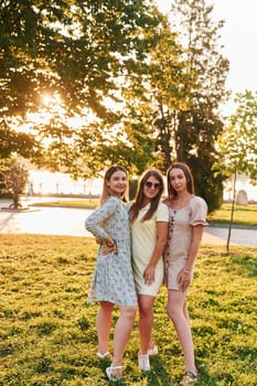 Three women standing in the autumn park together. Beautiful sunshine.