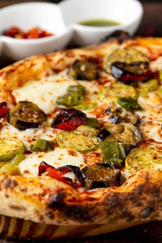 Vegetarian pizza with eggplant, zucchini and mushrooms on dark stone table