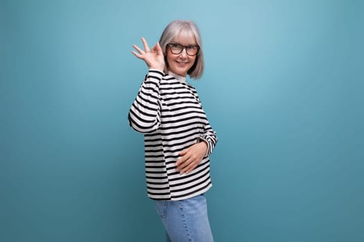 portrait of a pleasant well-groomed slender middle-aged grandmother with gray hair in a youth look on a bright studio background.