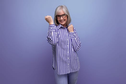 successful cheerful 60s middle aged woman in trendy shirt on bright studio background with copyspace.