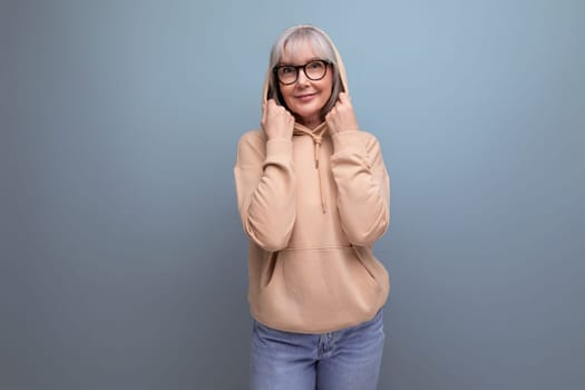 portrait of a kind middle-aged woman grandmother with gray hair in a casual youth look on a studio background with copy space.
