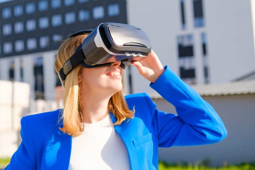 Smiling woman in vr glasses experiencing augmented reality in front of a business center. Futuristic future in the metaverse world.