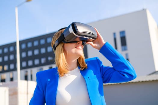 Smiling woman in vr glasses experiencing augmented reality in front of a business center. Futuristic future in the metaverse world.