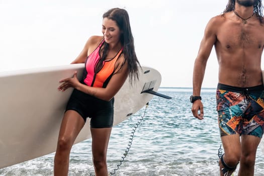 Sea woman and man on sup. Silhouette of happy young woman and man, surfing on SUP board, confident paddling through water surface. Idyllic sunset. Active lifestyle at sea or river