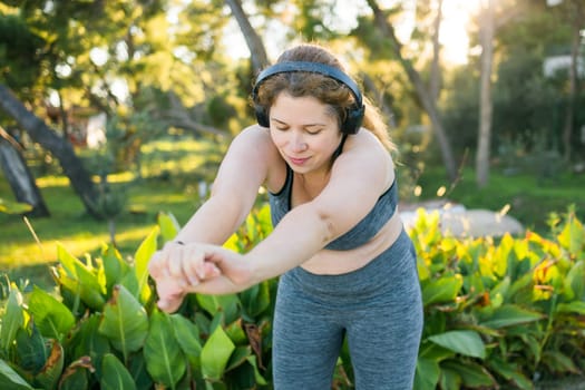 Young pretty smiling plus size woman in sporty top and leggings doing sport in summer outdoor