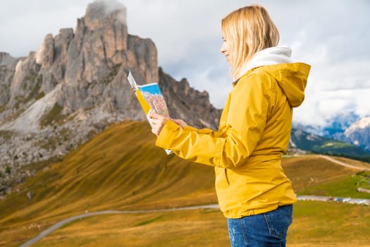 Young woman in a sport jacket navigating with map in the Dolomites Alps.