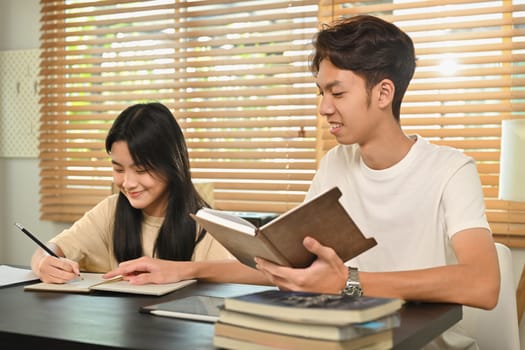 Male tutor giving private educational lesson to teenage asian girl. Homeschooling and education concept.