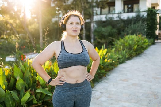 Fat woman and sports. Girl doing exercise for weight loss in the fresh air and laughing in camera after training.