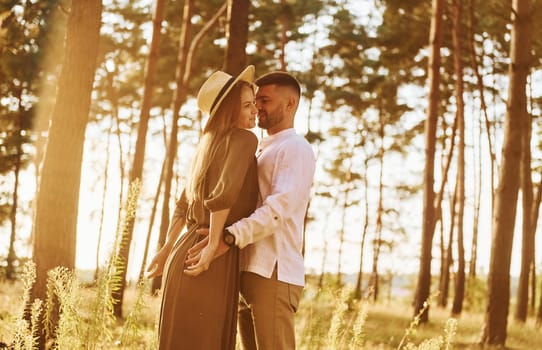 Embracing each other. Happy couple is outdoors in the forest at daytime.