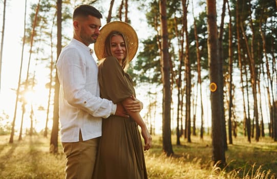 Beautiful sunlight. Happy couple is outdoors in the forest at daytime.