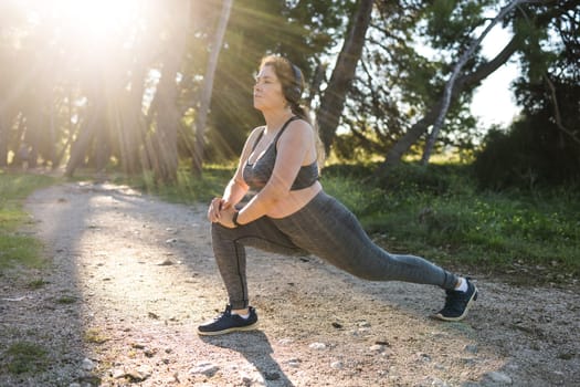 Young pretty smiling plus size woman in sporty top and leggings doing sport in summer outdoor