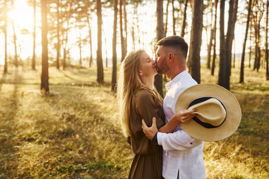 Embracing and kissing. Happy couple is outdoors in the forest at daytime.