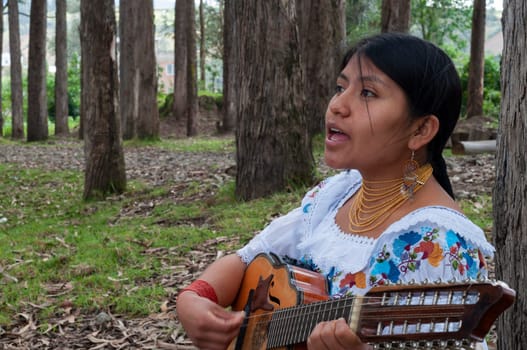 Closeup de una joven nativa cantando y tocando la mandolina en el bosque. High quality photo