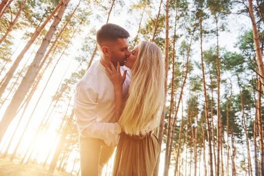 Warm weather. Happy couple is outdoors in the forest at daytime.