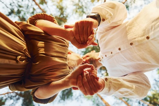 View from below. Happy couple is outdoors in the forest at daytime.