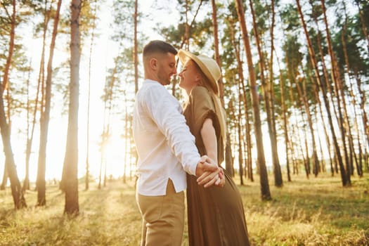 Warm weather. Happy couple is outdoors in the forest at daytime.