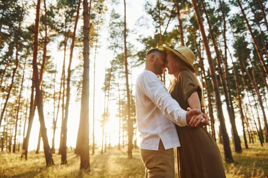 Warm weather. Happy couple is outdoors in the forest at daytime.