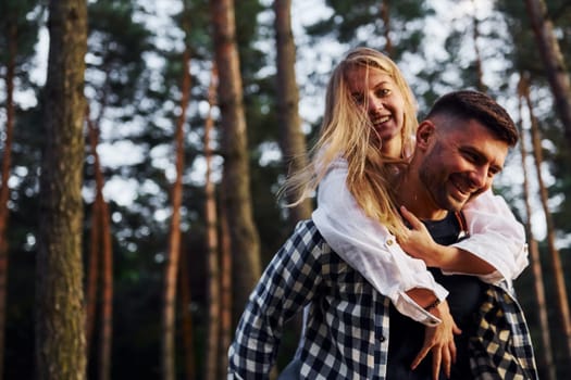 Happy couple is outdoors in the forest at daytime.