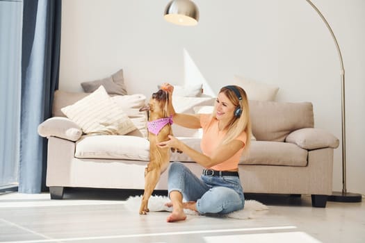 Playing with pet. Woman with pug dog is at home at daytime.