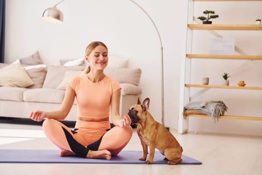 Having a rest. Woman with pug dog is at home at daytime.