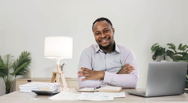 Portrait of handsome African black young business man working on laptop at office desk...